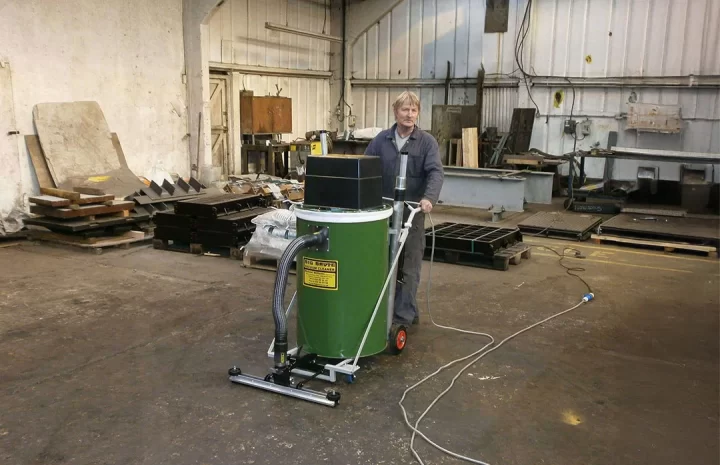 Operator using industrial vacuum cleaner to clean warehouse floor efficiently